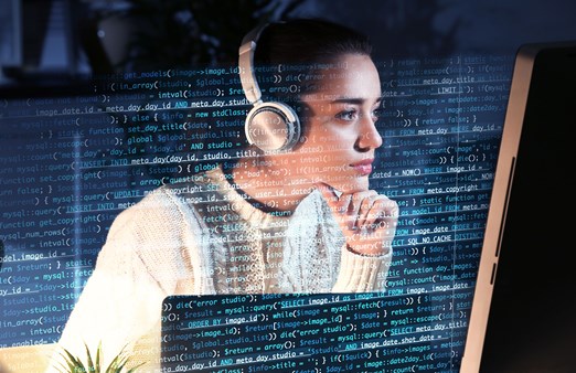 Woman wearing headphones and looking at data on a computer