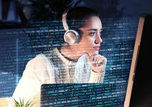 Woman wearing headphones and looking at data on a computer