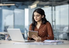 Female student holding a notebook while working on a laptop