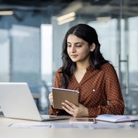 Female student holding a notebook while working on a laptop