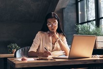 woman writing and studying in front of laptop