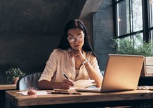 woman writing and studying in front of laptop