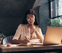 woman writing and studying in front of laptop