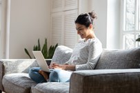smiling women sat on the sofa working on her laptop