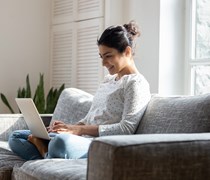 smiling women sat on the sofa working on her laptop