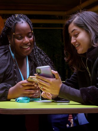 Two students smiling and looking at a phone