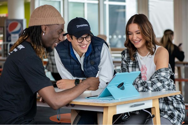 Group of students smiling and looking at an iPad