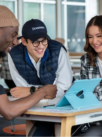 Group of students smiling and looking at an iPad