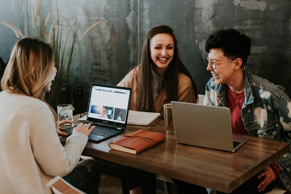 A group of students laughing whilst studying on laptops