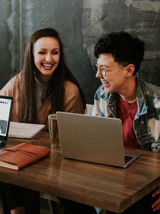 A group of students laughing whilst studying on laptops