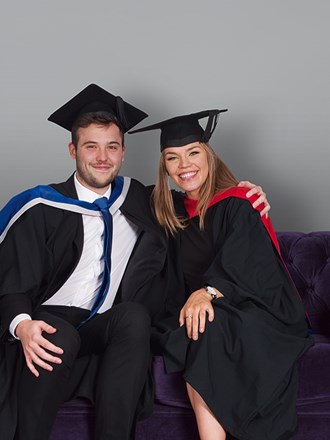 Two University of Law graduates sitting on a sofa Two University of Law graduates sitting on a sofa