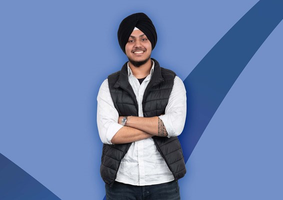 Student with arms crossed and smiling on on a blue coloured background