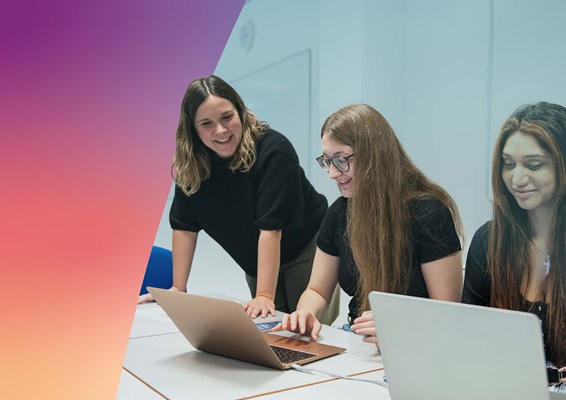 Three students in a classroom working on laptops