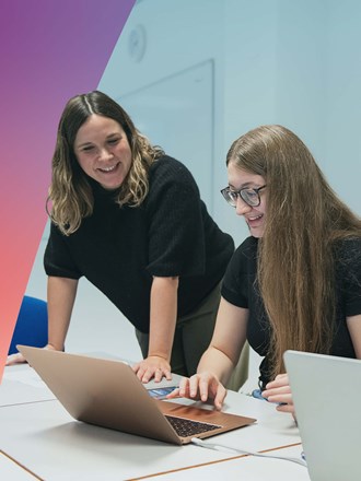 Three students in a classroom working on laptops